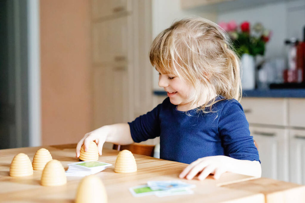 Adorable cute toddler girl playing parlor game. Happy healthy child training memory, thinking. Creative indoors leisure and education of kid during pandemic coronavirus covid quarantine disease - Photo, Image