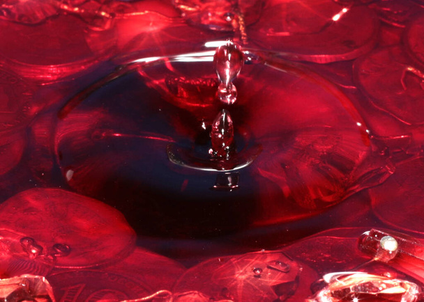 a drop of red liquid falls on the water surface and a bunch of Russian metal rubles - Foto, Imagen