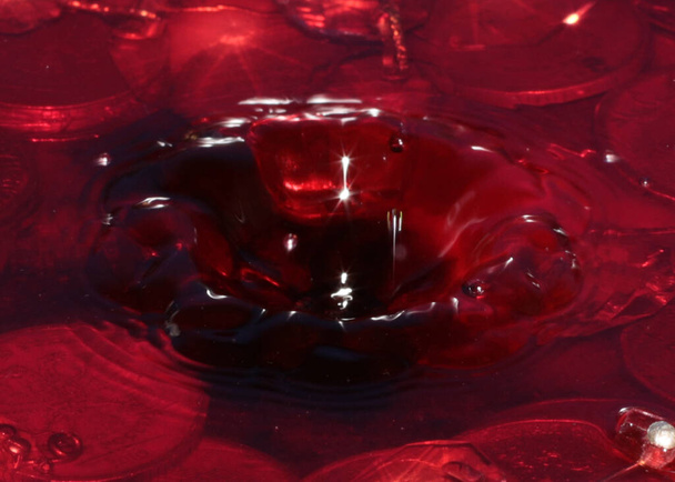 a drop of red liquid falls on the water surface and a bunch of Russian metal rubles - Fotografie, Obrázek