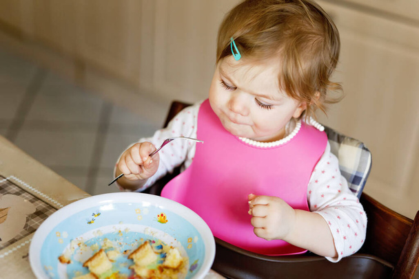 Entzückendes kleines Mädchen, das aus einem Löffel püriertem Gemüse und Püree isst. Ernährungs-, Kinder-, Ernährungs- und Personenkonzept - Foto, Bild