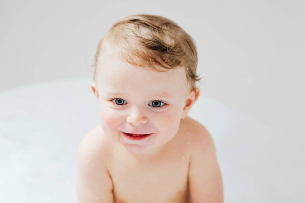 Bonito bebê adorável criança tomando banho na banheira em casa. Menino ou menina saudável feliz jogando, espirrando e se divertindo durante a hora do banho. Conceito de higiene e limpeza para bebês. - Foto, Imagem