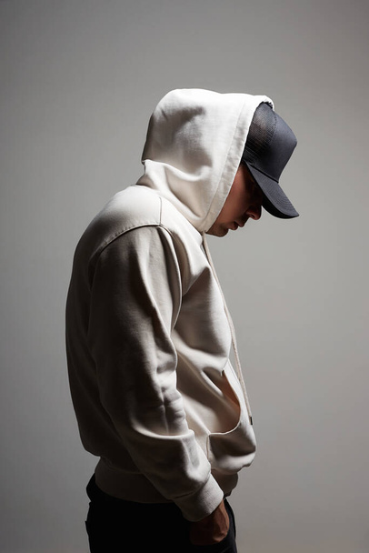 Young Man in Hat and Hood. Boy in a hooded sweatshirt posing in studio - Photo, Image