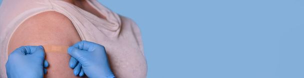 Un médecin portant des gants médicaux protecteurs met un plâtre à la main d'une femme âgée après une injection de vaccin ou une égratignure. Santé, premiers secours, concept de vaccination. Vaccination contre le coronavirus - Photo, image