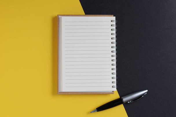 Jegyzetfüzet és toll fekete-sárga háttérrel, felülnézet - Fotó, kép