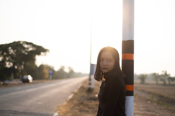 Gün batımında, uzun yolun kenarında duran güzel bir kız portresi.. - Fotoğraf, Görsel