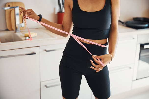 Sportowa młoda kobieta mierzy talię w domu - Zdjęcie, obraz