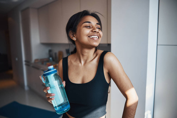 Cheerful young woman holding bottle of water - Foto, Imagem