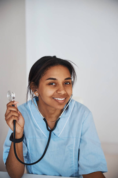 Stetoskop tutan, tıp üniformalı neşeli genç bir kadın. - Fotoğraf, Görsel