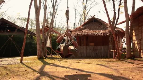 Egy turista játszik a hagyományos swing a faluban a Lua törzs Chiang Rai Thaiföld - Felvétel, videó