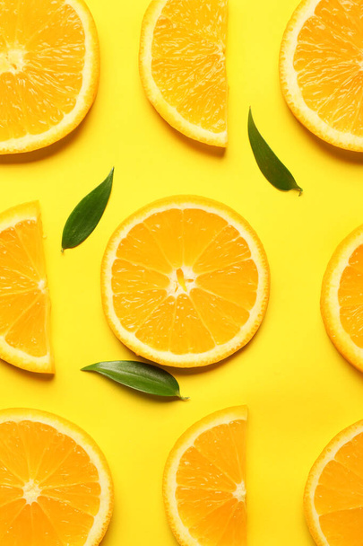 Slices of fresh oranges with green leaves on color background - Foto, Imagem