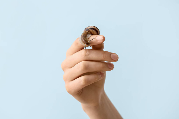 Hand with snail on light background - Zdjęcie, obraz