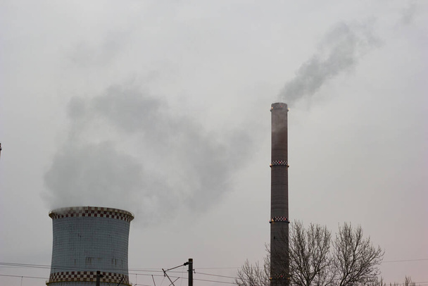 Κλίβανοι σταθμών παραγωγής ενέργειας με καύση άνθρακα που εκπέμπουν ατμό σε γκρίζα συννεφιασμένη ημέρα. - Φωτογραφία, εικόνα