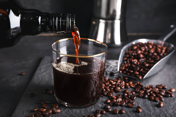 Pouring of tasty cold brew from bottle into glass on dark background, closeup - Photo, Image