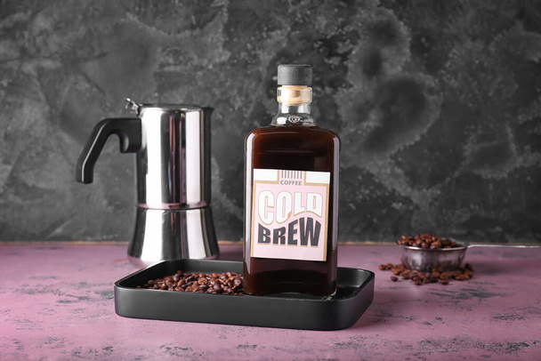 Samenstelling met fles smakelijk koud brouwsel en koffiebonen op donkere achtergrond - Foto, afbeelding