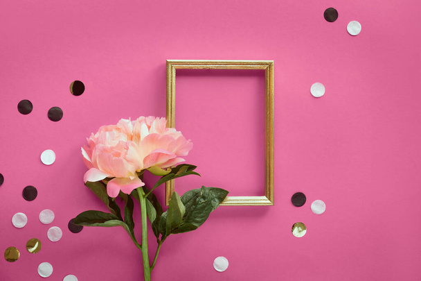 Pink peony flower, greeting card, golden frame. Minimal simple flat lay on abstract pink geometric background with paper confetti, polka dots. Confetti around frame, copy-space, place for text. - 写真・画像