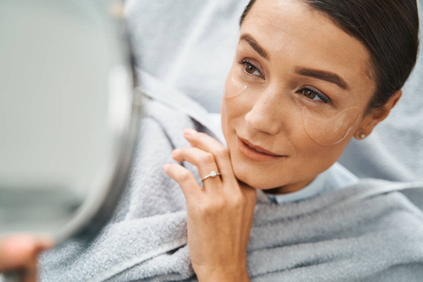 oncentrated beauty salon client examining her facial skin - Valokuva, kuva