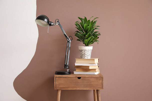 Дерев "яний стіл з лампою та домашньою рослиною біля кольорової стіни. - Фото, зображення