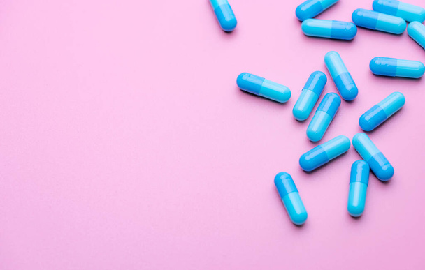 Blue capsule pills on pink background. Blue capsule pills with copy space. Pharmaceutical industry. Community pharmacy product. Drug use in pregnancy woman and lactation and elderly people topics. - Photo, Image