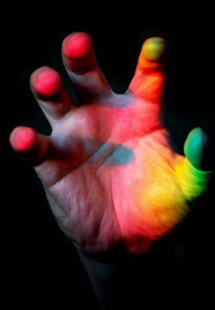 mano multicolor sobre fondo negro - Foto, imagen