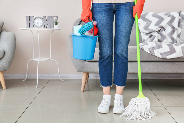 Mujer joven con artículos de limpieza en la habitación - Foto, imagen