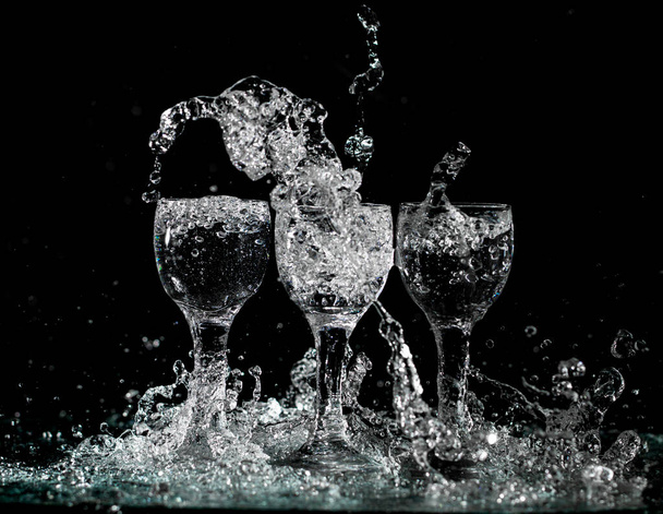 glasses with water with splashes on a black background - Foto, afbeelding