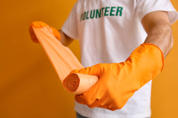 Volunteer with garbage bags on color background - Foto, Bild