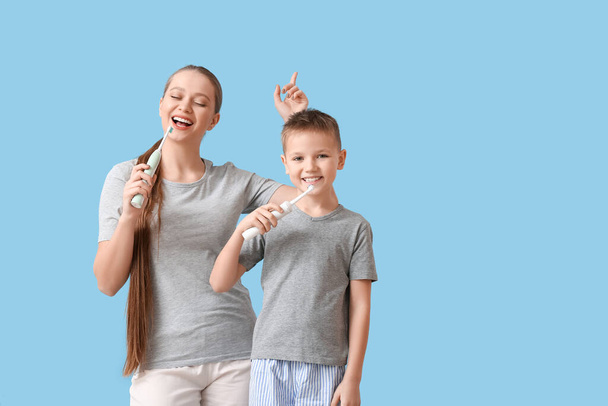 Mother and little son brushing teeth on color background - Photo, Image