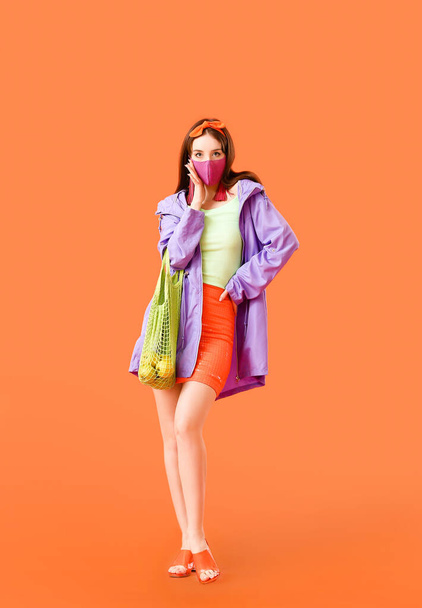 Fashionable young woman wearing mask on color background - Фото, зображення