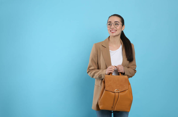 Beautiful young woman with stylish leather backpack on turquoise background. Space for text - Fotografie, Obrázek