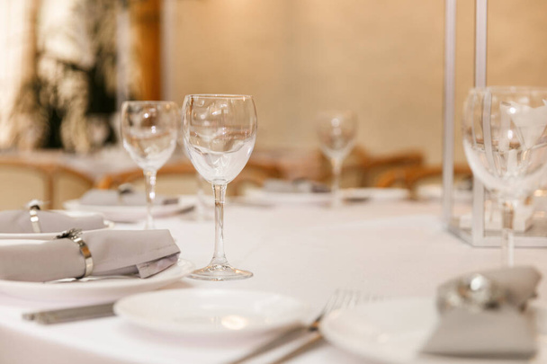 Feestelijke Floral decor op bruiloft banket tafels in witte kleuren met bestek. Met verschillende natuurlijke kleuren rozen, pioenen, anthurium. Luxe bruiloft, feest, verjaardag. - Foto, afbeelding