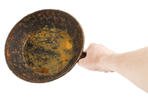 γυμνό καυκάσιο χέρι που κρατά άδειο παλιό τηγάνι από χυτοσίδηρο - Φωτογραφία, εικόνα