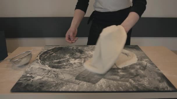 Primer plano de una forma manual de preparar los fundamentos de la pizza en un café y el chef gira la masa en sus manos - Metraje, vídeo