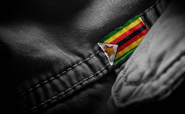 Markering op donkere kleding in de vorm van de vlag van Zimbabwe - Foto, afbeelding