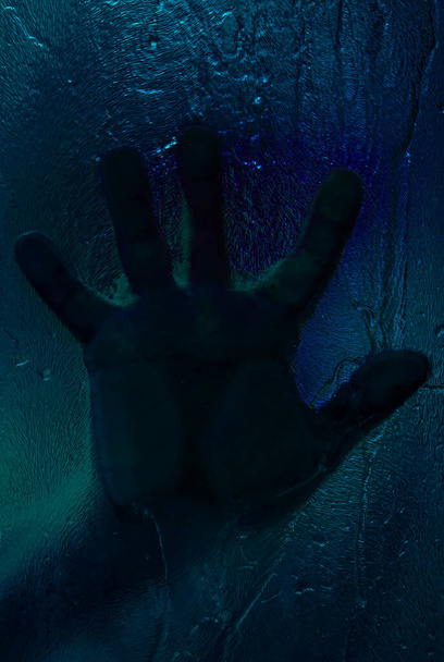 Mão ensanguentada contra vidro de chuveiro molhado. Conceito de horror. Imagem tonificada. Imagem vertical - Foto, Imagem