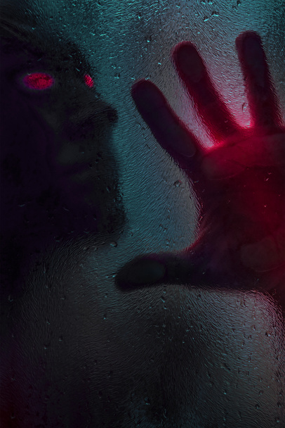 Horror jelenet egy véres kezű férfiról nedves zuhanyüveggel szemben. Hangos kép. Horror koncepció. Függőleges kép - Fotó, kép