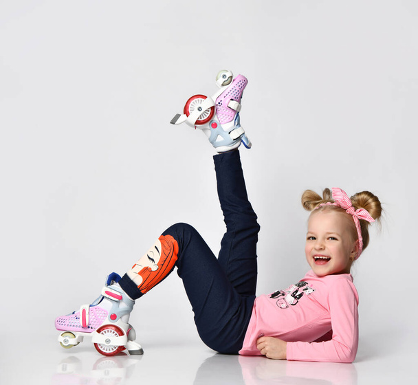 Full body portrait funky girl wearing on roller skates sitting on studio floor - Фото, изображение