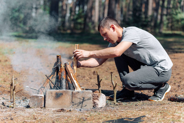 a man lights a fire. family vacation in nature - Foto, Imagen