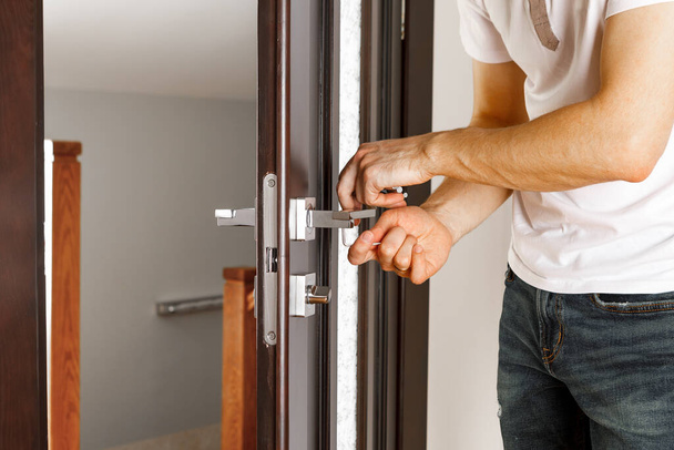 a man repairing a doorknob - Фото, изображение