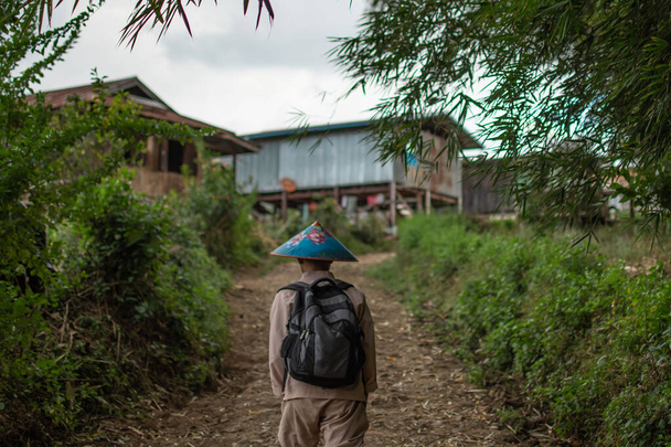 Бірманська людина в традиційному одязі і барвистий синій капелюх йдуть через місцеве село від Калава до озера Інле, штат Шань, М'янма - Фото, зображення