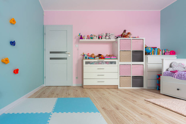 Sala de juegos para niños turquesa y rosa con pared de escalada y juguetes - Foto, Imagen