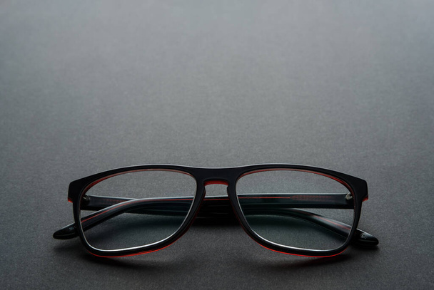 Stylish men's glasses in a black frame on black background. Eyesight. - Фото, зображення