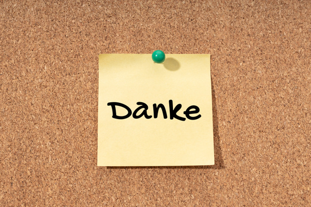 Thanks word in german language on yellow note on cork board - Photo, Image