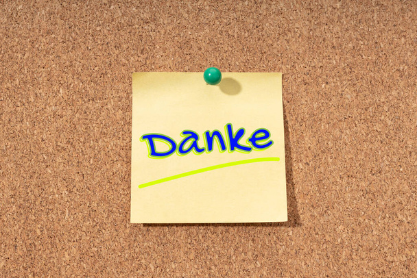 Слово благодарности на немецком языке на желтой ноте на пробковой доске - Фото, изображение