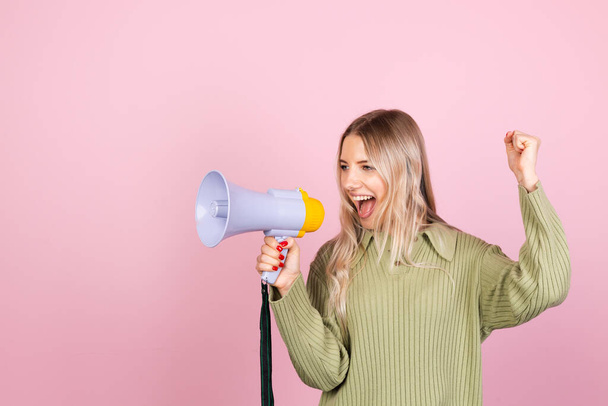 Pretty european woman in casual sweater on pink background happy screaming in megaphone copy space - Фото, изображение