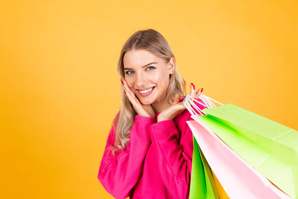 Mulher muito europeia em blusa rosa no fundo amarelo segurando sacos de compras chocado espantado animado espaço cópia isolada - Foto, Imagem