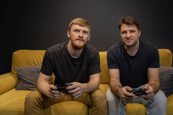 zwei gut gelaunte Kerle spielen leidenschaftlich Videospiel mit Konsolen-Gamepad - Foto, Bild