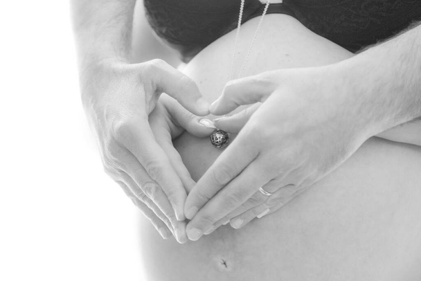 Italien, April 2021. Ausschnittbild der schönen schwangeren Frau und ihres hübschen Mannes, der ihren Bauch umarmt - Foto, Bild
