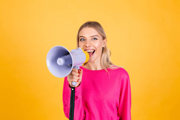 Pretty european woman in pink  blouse on yellow background happy funny screaming in megaphone cheerful with big sweet smile excited amazed - Фото, зображення