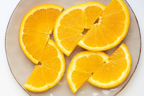 Dokonale nakrájené pomeranče na šedý talíř. Půlkruhy pomerančů na talíři. Nasycené pomeranče jsou krájeny na talíři - Fotografie, Obrázek