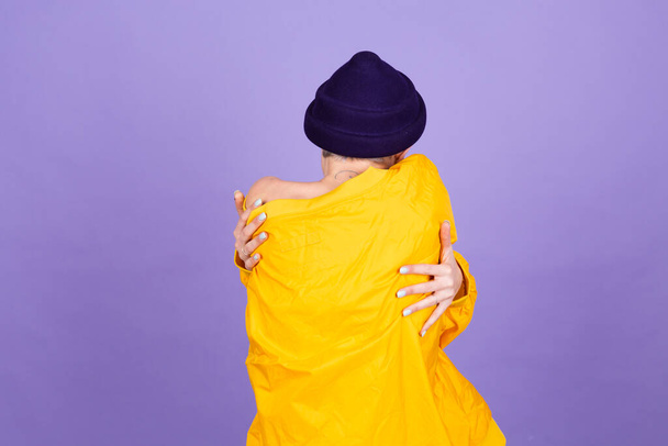 紫の背景にスタイリッシュなヨーロッパの女性自己ケアとともに自分自身を抱き笑顔と閉じた目 - 写真・画像